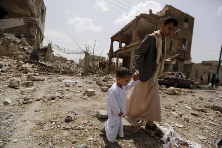 A man and a boy walk at a site hit by a Saudi-led air strike in Yemen's capital